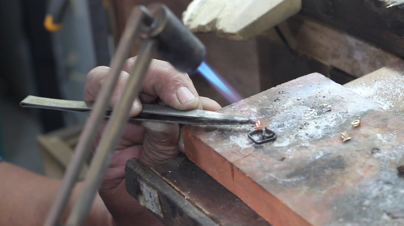 A flower petal detail being heated and then hammered into a precise form.